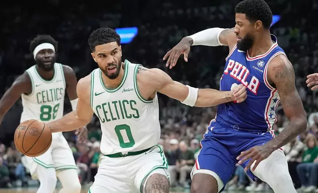 Boston Celtics forward Jayson Tatum (0) drives against Philadelphia 76ers forward Paul George, right, during the first half in Game 1 of a first-round NBA playoffs basketball game, Sunday, April 19, 2026, in Boston. (AP Photo/Robert F. Bukaty)