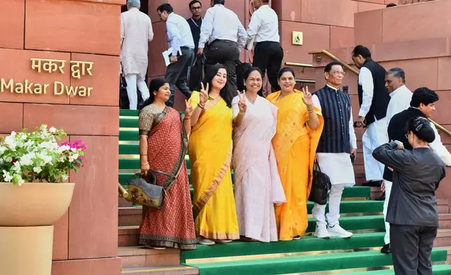 A security officer takes photograph of Indian women lawmakers as they pose outside Parliament House before the start of the debate on a landmark bill to reserve one-third of seats for women, in New Delhi, India, Thursday, April 16, 2026. (AP Photo)