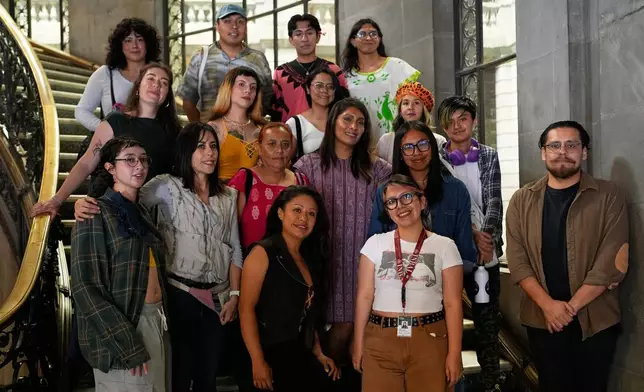 People pose for a photo after a backstrap loom workshop for LGBTQ+ people by Muxe artist Xaneri Merino, in purple, in Mexico City, Tuesday, April 14, 2026. (AP Photo/Marco Ugarte)