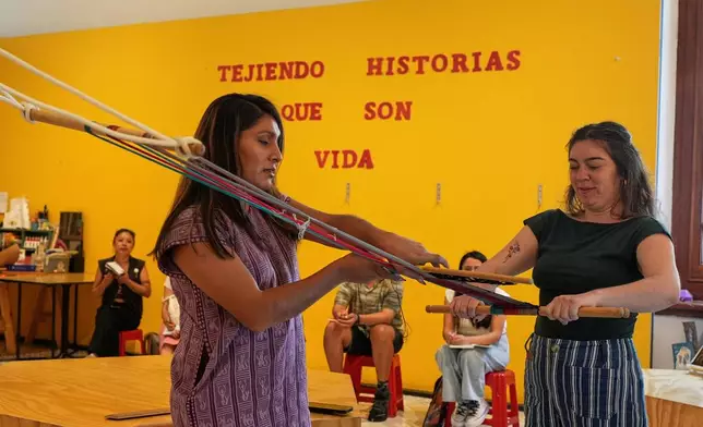 Muxe artist Xaneri Merino, left, gives a backstrap loom workshop for LGBTQ+ people in Mexico City, Tuesday, April 14, 2026. (AP Photo/Marco Ugarte)