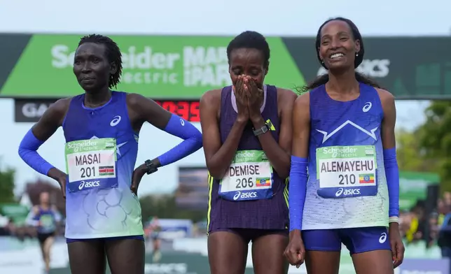 From left, Kenya's Magdalyne Masai, Ethiopia's Shure Demise and Ethiopia's Misgane Alemayehu pose after crossing the finish line of the women's race of the Paris marathon, in Paris, Sunday, April 12, 2026. (AP Photo/Thibault Camus)
