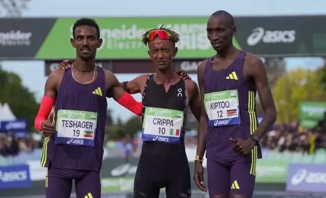 From left, Ethiopia's Bayelign Teshager, Italy's Yemaneberhan Crippa and Kenya's Sila Kiptoo pose after crossing the finish line of the men's race of the Paris marathon, in Paris, Sunday, April 12, 2026. (AP Photo/Thibault Camus)