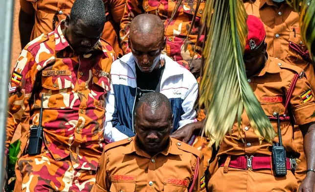 Christopher Okello Onyum, a man accused of killing four children, is escorted in court at the Ggaba Community Church grounds in Kampala, Uganda, Monday, April 13, 2026. (AP Photo/Hajarah Nalwadda)