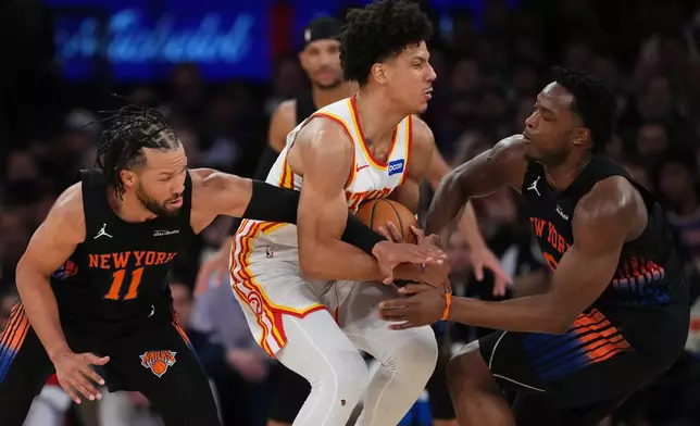 New York Knicks' Jalen Brunson, left, and OG Anunoby, right, defend Atlanta Hawks' Jalen Johnson, center, during the first half in Game 5 of a first-round NBA playoffs basketball series, Tuesday, April 28, 2026, in New York. (AP Photo/Frank Franklin II)