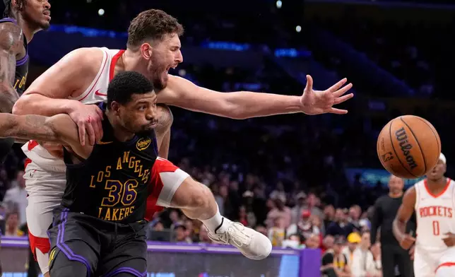 Houston Rockets center Alperen Sengun, top, and Los Angeles Lakers guard Marcus Smart go after a rebound during the first half in Game 2 of a first-round NBA playoffs basketball series Tuesday, April 21, 2026, in Los Angeles. (AP Photo/Mark J. Terrill)