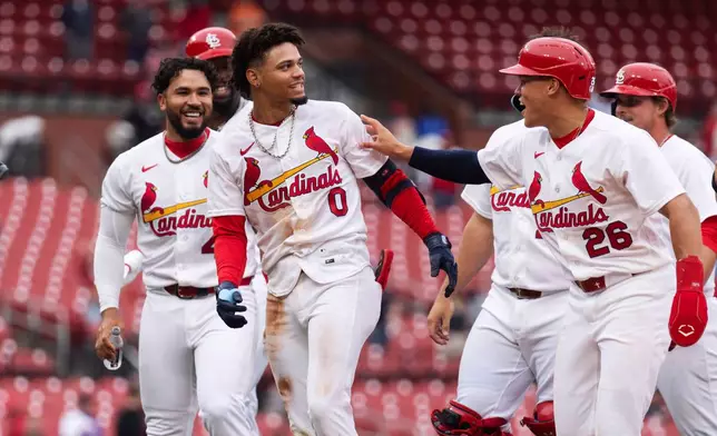St. Louis Cardinal teammates surround Masyn Winn after he hit the game winning hit during the eleventh inning of a baseball game against the New York Mets Wednesday, April 1, 2026, in St. Louis. (AP Photo/LG Patterson)