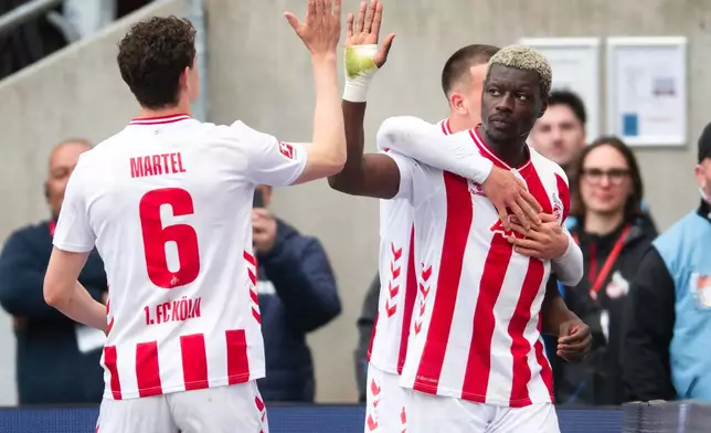 Koln's Ragnar Ache, right, celebrates with Eric Martel, left, after scoring his side's second goal during German Bundesliga soccer match between 1. FC Koln and Werder Bremen and Werder Bremen, in Cologne, Germany, Sunday, April 12, 2026. (Marius Becker/dpa via AP)