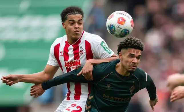 Koln's Jahmai Simpson-Pusey, left, and Werder Bremen's Justin Njinmah challenge for the ball during German Bundesliga soccer match between 1. FC Koln and Werder Bremen and Werder Bremen, in Cologne, Germany, Sunday, April 12, 2026. (Marius Becker/dpa via AP)