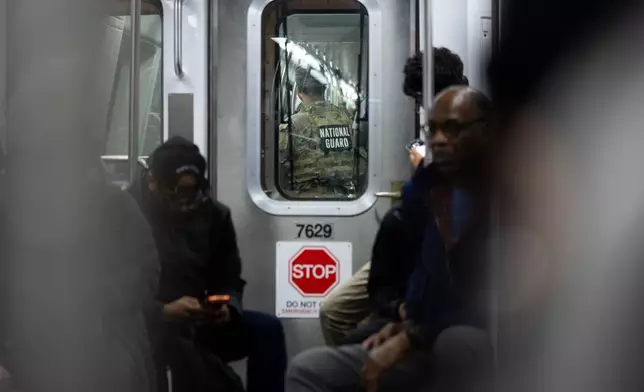FILE - A member of the National Guard rides the Metro, March 23, 2026, in Washington. (AP Photo/Allison Robbert, File)