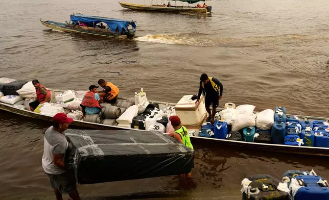 Boatmen operating Catraia, a traditional boat used on the Oiapoque River, prepare for a crossing carrying goods, gasoline canisters and supplies, at a port in the city of Oiapoque, Amapa state, Brazil, Tuesday, March 10, 2026. (AP Photo/Eraldo Peres)