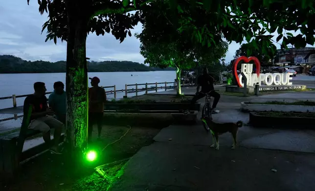 Residents chat at dusk on the banks of the Oiapoque River, in Oiapoque, Amapa state, Brazil, Monday, March 9, 2026. (AP Photo/Eraldo Peres)