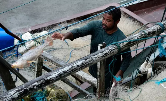 A fisher works on his boat unloading a catch at the fish trading port on the banks of the Oiapoque River in the city of Oiapoque, Amapa state, Brazil, Tuesday, March 10, 2026. (AP Photo/Eraldo Peres)