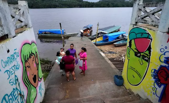 A family talks as they arrive at a port on the banks of the Oiapoque River, in the city of Oiapoque, Amapa state, Brazil, Monday, March 9, 2026. (AP Photo/Eraldo Peres)