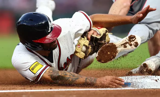 Atlanta Braves designated hitter Dominic Smith, left, is tagged out by Miami Marlins third baseman Graham Pauley, right, in the third inning of a baseball game, Monday, April 13, 2026, in Atlanta. (AP Photo/Colin Hubbard)