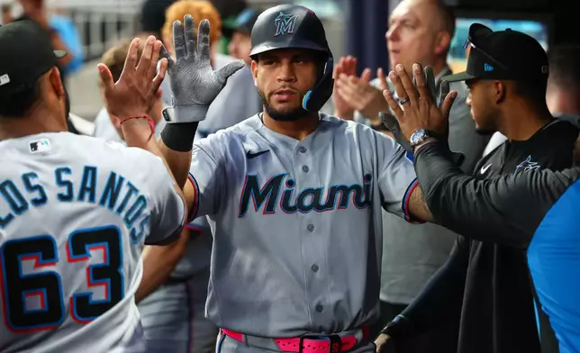 Miami Marlins' Agustín Ramírez, center, high-fives teammates in the dugout after scoring a run in the fourth inning of a baseball game against the Atlanta Braves, Monday, April 13, 2026, in Atlanta. (AP Photo/Colin Hubbard)