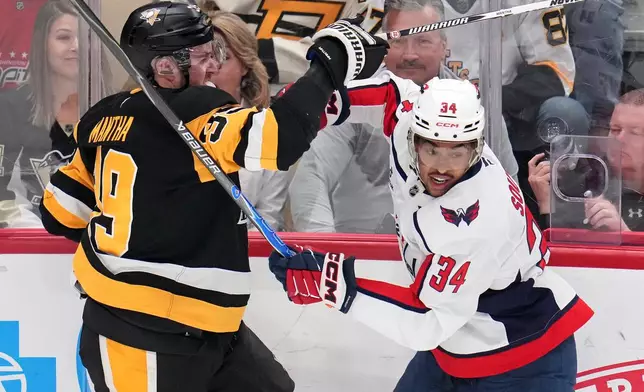 Washington Capitals' Justin Sourdif (34) battles Pittsburgh Penguins' Anthony Mantha (39) during the first period of an NHL hockey game in Pittsburgh, Saturday, April 11, 2026. (AP Photo/Gene J. Puskar)