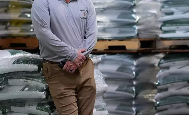 Top Class Lawn Care owner Jake Wilson stands by fertilizer he stockpiled at his supplier's warehouse in anticipation of Iran war related price hikes Thursday, March 26, 2026, in Riverside, Mo. (AP Photo/Charlie Riedel)