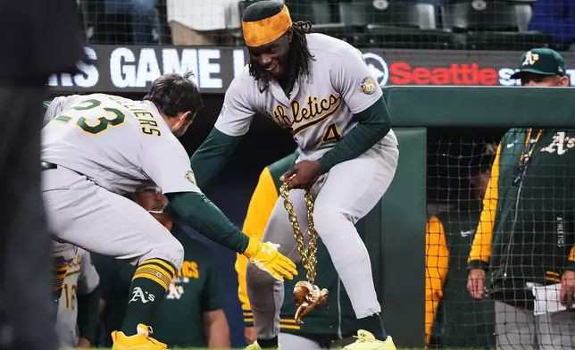 Athletics' Shea Langeliers (23) is greeted by Lawrence Butler (4), holding a gold elephant chain, as they celebrate Langeliers' solo home run against the Seattle Mariners during the seventh inning of a baseball game, Tuesday, April 21, 2026, in Seattle. (AP Photo/Lindsey Wasson)