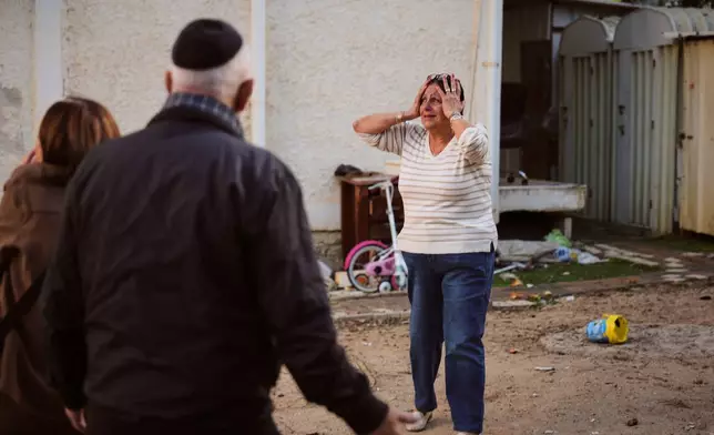 FILE - A woman reacts at the site of a damaged residential building after it was struck by a projectile fired from Lebanon, in Nahariya, northern Israel Monday, April 13, 2026. (AP Photo/Ariel Schalit, File)