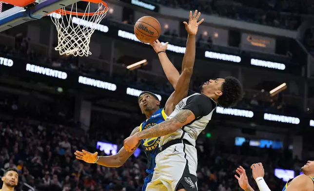 San Antonio Spurs guard Dylan Harper, right, drives to the basket against Golden State Warriors guard Nate Williams, left, during the first half of an NBA basketball game in San Francisco, Wednesday, April 1, 2026. (AP Photo/Tony Avelar)