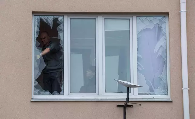 People remove broken glass from their windows after a Russian strike on residential neighbourhood in Kriukivshchyna, Kyiv region, Ukraine, on Friday, April 3, 2026. (AP Photo/Evgeniy Maloletka)