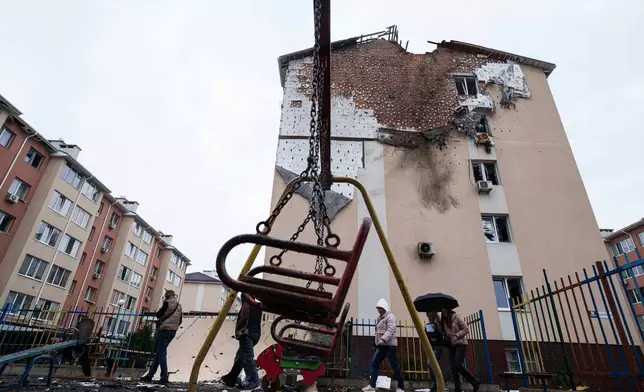 People walk in front of a house which was damaged after a Russian strike on residential neighbourhood in Kriukivshchyna, Kyiv region, Ukraine, on Friday, April 3, 2026. (AP Photo/Evgeniy Maloletka)