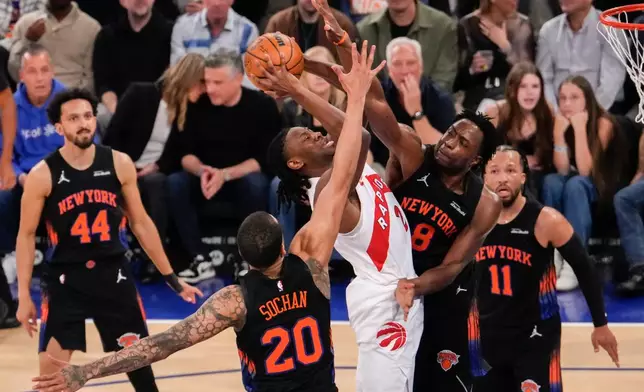 Toronto Raptors forward Jonathan Mogbo (2) shoots over New York Knicks forward Og Anunoby (8) and New York Knicks forward Jeremy Sochan (20) during the first half of an NBA basketball game, Friday, April 10, 2026, in New York. (AP Photo/Yuki Iwamura)