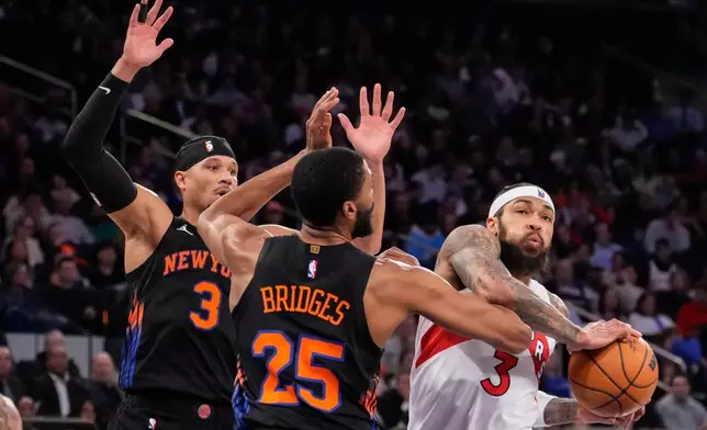 Toronto Raptors forward Brandon Ingram (3) drives past New York Knicks guard Mikal Bridges (25) and New York Knicks guard Josh Hart (3) during the first half of an NBA basketball game, Friday, April 10, 2026, in New York. (AP Photo/Yuki Iwamura)
