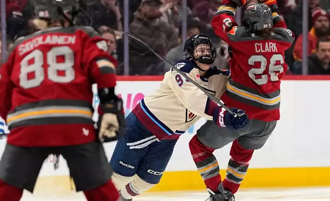 Montreal Victoire's Maggie Flaherty (91) knocks Ottawa Charge's Emily Clark (26) off her skates during second-period PWHL hockey game action in Ottawa, Ontario, Friday, April 3, 2026. (Justin Tang/The Canadian Press via AP)
