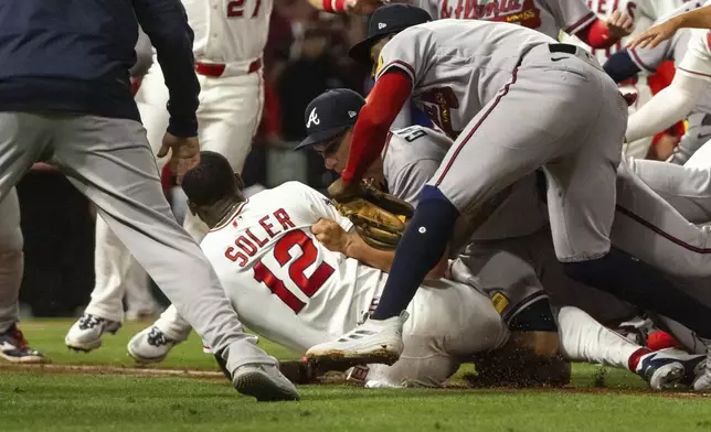 Los Angeles Angels' Jorge Soler (12) is tackled to the ground by Atlanta Braves players as a fight breaks out during the fifth inning of a baseball game, Tuesday, April 7, 2026, in Anaheim, Calif. (AP Photo/Ethan Swope)
