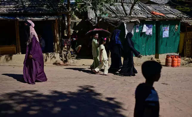 FILE - Rohingya refugee women and children walk along a street in the Rohingya refugee camp in Cox's Bazar, Bangladesh, Nov. 21, 2025. (AP Photo/Mahmud Hossain Opu, File)