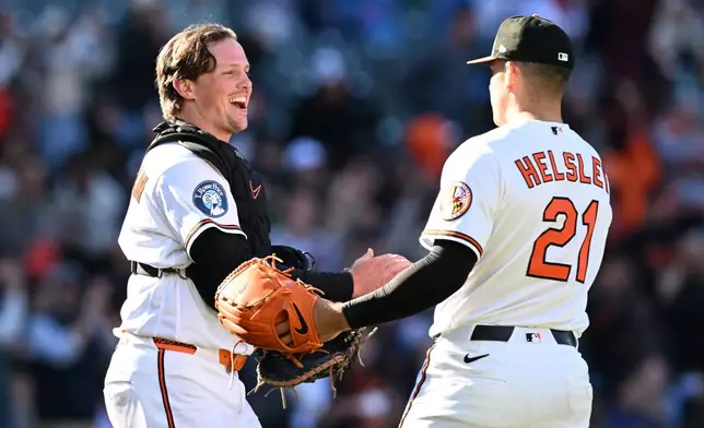 Baltimore Orioles catcher Adley Rutschman, left, and pitcher Ryan Helsley celebrate their 8-6 win over the Minnesota Twins in a baseball game, Sunday, March 29, 2026 in Baltimore. (AP Photo/Gail Burton)