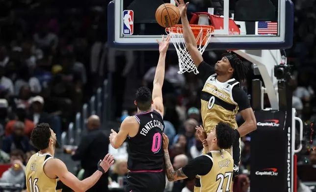 Miami Heat forward Simone Fontecchio, center, goes to the basket and attempts a layup but has his shot blocked by Washington Wizards guard Bilal Coulibaly, top right, while being fouled by Wizards guard Will Riley (27) during the first half of an NBA basketball game, Friday, April 10, 2026, in Washington. (AP Photo/Terrance Williams)