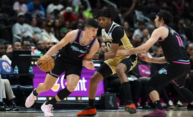 Miami Heat forward Simone Fontecchio, left, handles the ball as Washington Wizards guard Bilal Coulibaly, center, defends during the first half of an NBA basketball game, Friday, April 10, 2026, in Washington. (AP Photo/Terrance Williams)