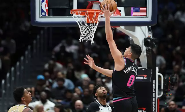 Miami Heat forward Simone Fontecchio (0) goes to the basket for a layup over Washington Wizards forward Leaky Black, second from right, during the first half of an NBA basketball game, Friday, April 10, 2026, in Washington. (AP Photo/Terrance Williams)