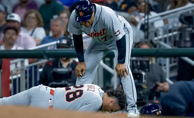 Detroit Tigers' Javier Baez (28) reacts after injuring his right leg running to first base on a ground ball against the Atlanta Braves, as Detroit Tigers first base coach Anthony Sanders (77) looks on during the fifth inning of a baseball game, Tuesday, April 28, 2026, in Atlanta. (AP Photo/Erik S. Lesser)