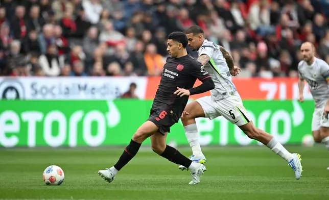 Leverkusen's Ezequiel Fernández, left, and Wolfsburg's Vinicius de Souza Costa in action during the Bundesliga soccer match between Bayer Leverkusen and VfL Wolfsburg in Leverkusen, Germany, Saturday April 4, 2026. (Fabian Strauch/dpa via AP)