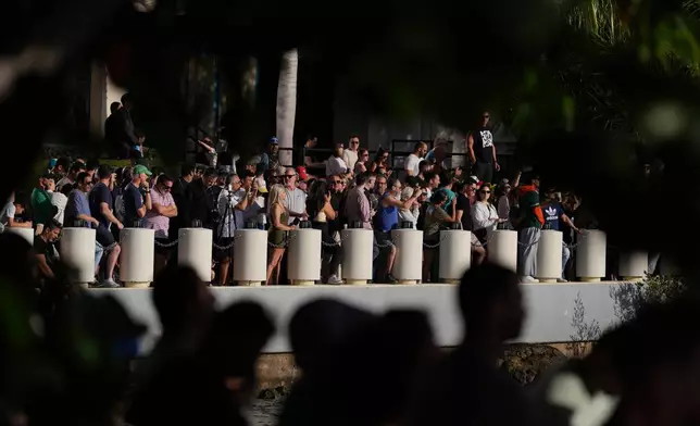 People gather along the Biscayne Bay waterfront to watch the controlled implosion of the former Mandarin Oriental Hotel on Brickell Key, Sunday, April 12, 2026, in Miami. (AP Photo/Rebecca Blackwell)
