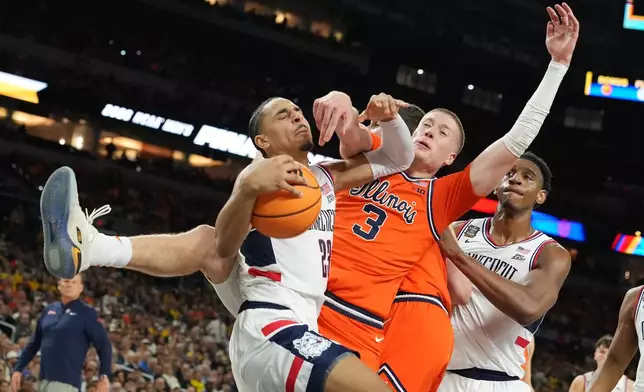 UConn's Jayden Ross (23) and Illinois' Ben Humrichous (3) battle for the ball during the first half of an NCAA college basketball tournament semifinal game at the Final Four, Saturday, April 4, 2026, in Indianapolis. (AP Photo/Michael Conroy)