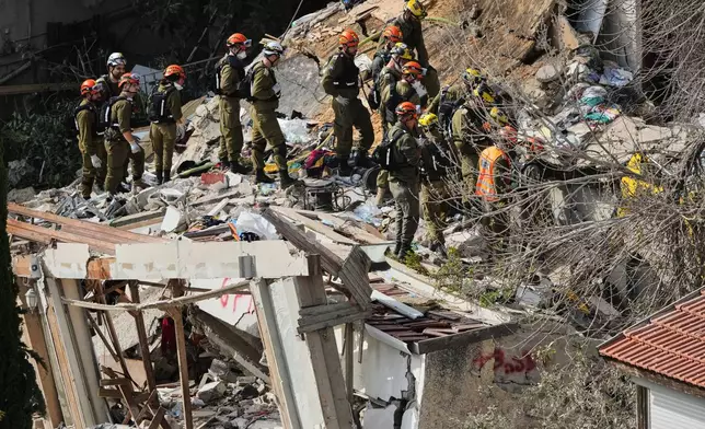 Israeli rescue teams search for missing people amid the rubble of a residential building a day after it was struck by an Iranian missile in Haifa, Israel, Monday, April 6, 2026. (AP Photo/Ariel Schalit)