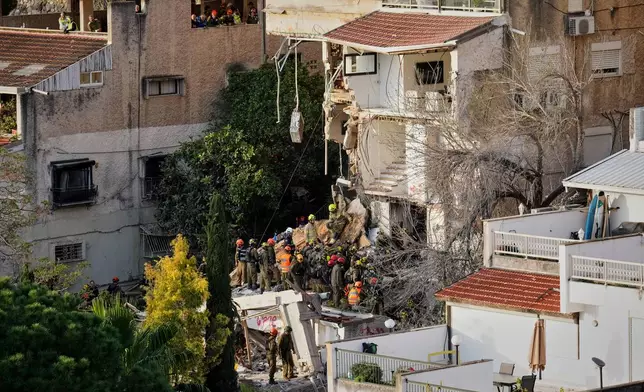 Israeli rescue teams search for missing people amid the rubble of a residential building a day after it was struck by an Iranian missile in Haifa, Israel, Monday, April 6, 2026. (AP Photo/Ariel Schalit)