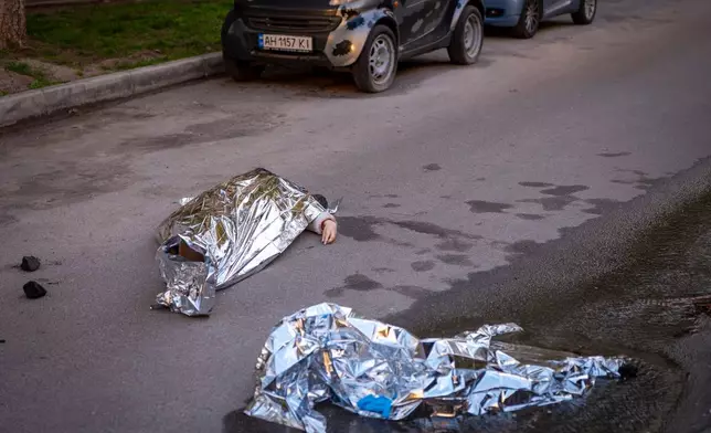 Bodies of victims are seen at the site where a gunman killed at least six people in the streets before being shot dead by police, in Kyiv, Ukraine, Saturday, April 18, 2026. (AP Photo/Dan Bashakov)