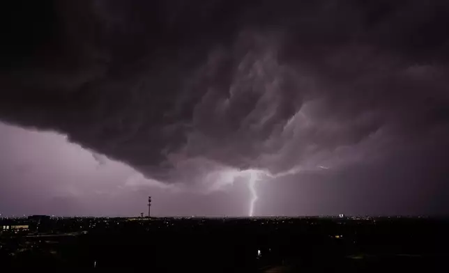 Lightning flashes as a thunderstorm passes in the distance Monday, April 13, 2026, in Lenexa, Kan. (AP Photo/Charlie Riedel)