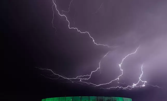 Lightning flashes beyond an office building as a thunderstorm passes in the distance, Monday, April 13, 2026, in Lenexa, Kan. (AP Photo/Charlie Riedel)