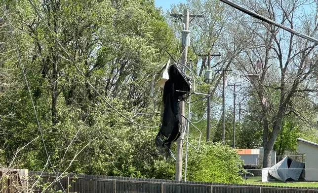 A trampoline is wrapped up in power lines behind a home in Ottawa, Kansas, Tuesday, April 14, 2026, after severe storms moved through the area. (AP Photo/Nick Ingram)