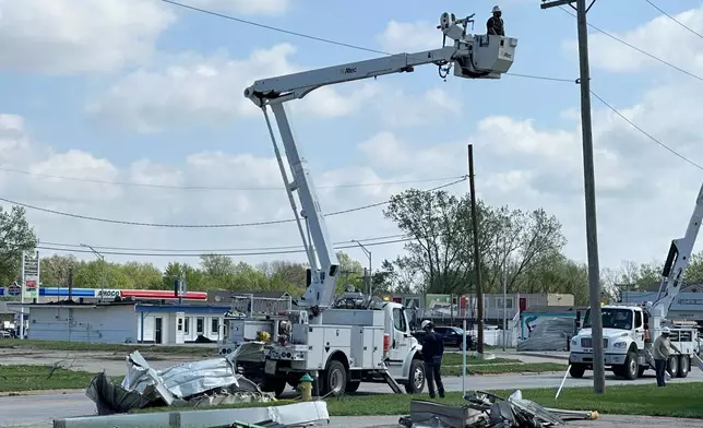 Crews work on power lines in Ottawa, Kansas, on Tuesday, April 14, 2026, following severe storms. (AP Photo/Nick Ingram)