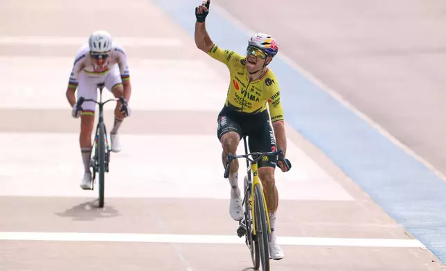 Belgium's Wout van Aert crosses the finish line ahead of Tadej Pogacar of Slovenia, left, to win the Paris-Roubaix cycling race in Roubaix, France, Sunday, April 12, 2026. Van Aert pointed his finger skywards to commemorate Belgian cyclist Michael Goolaerts who died after crashing in the race in 2018. (AP Photo/Jean-Francois Badias)