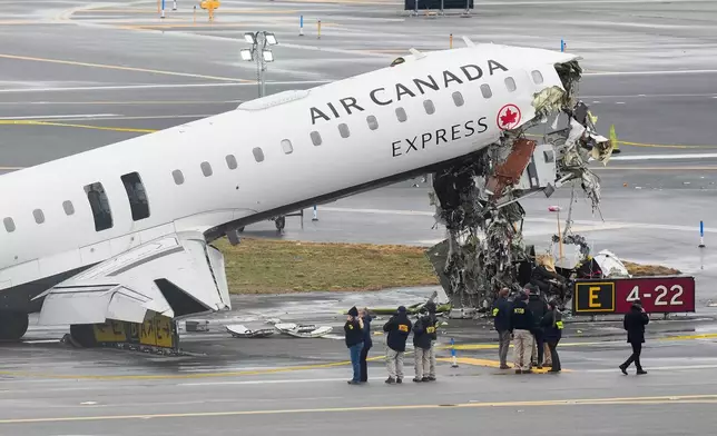 FILE - Officials with the National Transportation Safety Board investigate the site on March 23, 2026, where an Air Canada jet came to rest after colliding with a Port Authority firetruck at LaGuardia Airport, shortly after landing in New York. (AP Photo/Seth Wenig, File)