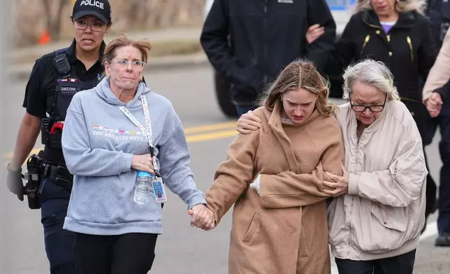 FILE- Law enforcement escort families away from the Temple Israel synagogue following an attack, March 12, 2026, in West Bloomfield Township, Mich. (AP Photo/Paul Sancya, File)