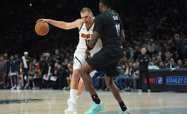 Denver Nuggets center Nikola Jokic, left, works toward the basket as Minnesota Timberwolves center Naz Reid (11) defends during the first half of Game 4 of a first-round NBA basketball playoff series, Saturday, April 25, 2026, in Minneapolis. (AP Photo/Abbie Parr)